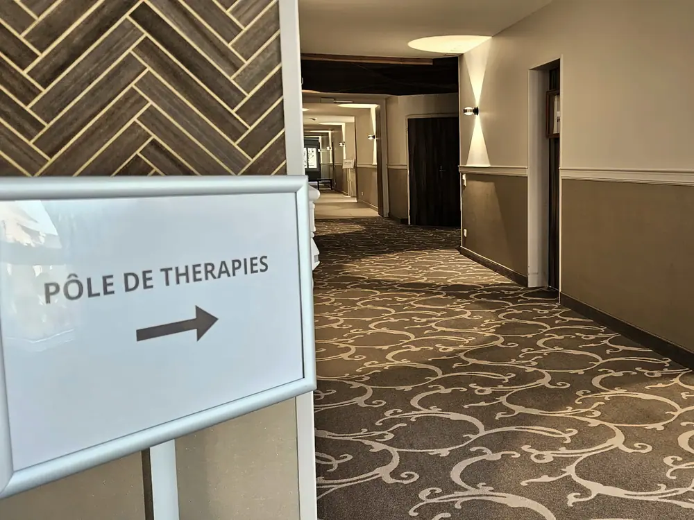Un couloir et un panneau « Pôle de thérapies » avec une flèche